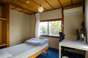 a room with a bed and a desk and a window at Yanagawa Guest House Horiwari in Yanagawa