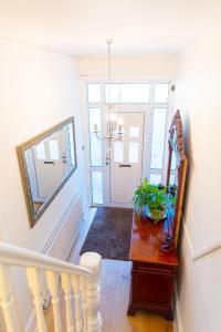 a hallway with a staircase with a mirror and a door at Rare London 6bedroom House in South Norwood