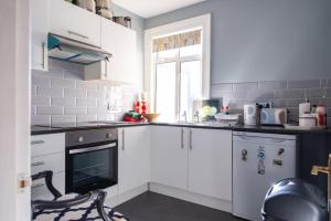 a kitchen with white cabinets and a window at Rare London 6bedroom House in South Norwood