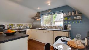 a kitchen with blue walls and a table with wine glasses at Waters Edge @ The Alleys in Atlow