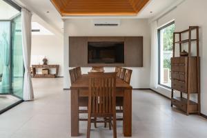 een eetkamer met een houten tafel en stoelen bij Sun Diego Resort Pool Villa in Jomtien Beach
