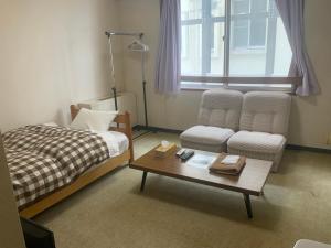 1 dormitorio con cama, sofá y mesa de centro en ロッヂ　スガノ en Zao Onsen