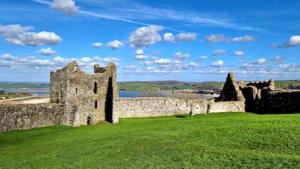 an old castle on a green field with a blue sky at The Lookout - Chalet 32 in Carmarthen