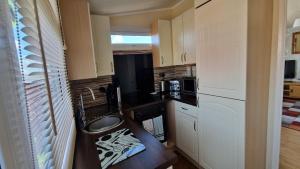 a small kitchen with a sink and a microwave at The Lookout - Chalet 32 in Carmarthen