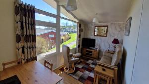 a living room with a couch and a tv and a window at The Lookout - Chalet 32 in Carmarthen