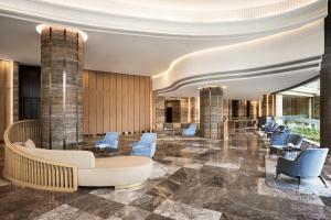 a lobby with blue chairs and a couch and tables at Sheraton Hai Phong in Hai Phong