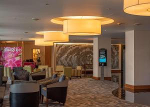 a lobby of a hotel with chairs and tables and lights at Hilton London Heathrow Airport Terminal 5 in Hillingdon