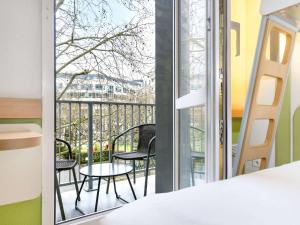 a bedroom with a balcony with chairs and a table at ibis budget Issy Les Moulineaux Paris Ouest in Issy-les-Moulineaux