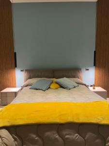 a bed with a yellow blanket and two pillows at Pergamena Bianca in Cava deʼ Tirreni