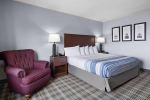 a hotel room with a bed and a chair at AmericInn by Wyndham Stuart in Stuart