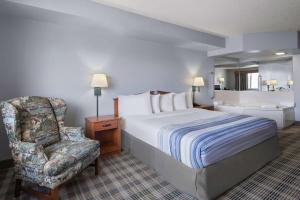 a hotel room with a bed and a chair at AmericInn by Wyndham Stuart in Stuart