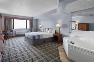 a hotel room with a bed and a bath tub at AmericInn by Wyndham Stuart in Stuart