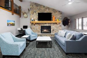 sala de estar con 2 sofás azules y chimenea en AmericInn by Wyndham Stuart, en Stuart