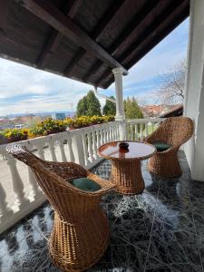 eine Veranda mit Korbstühlen und einem Tisch auf dem Balkon in der Unterkunft International Inn in Paraćin