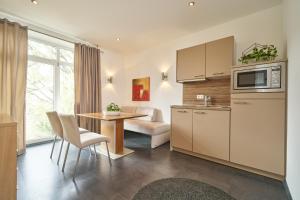 eine Küche und ein Wohnzimmer mit einem Tisch und einem Sofa in der Unterkunft Hotel am Hof in Taufkirchen