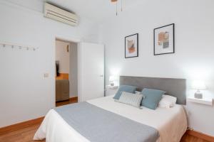 ein weißes Schlafzimmer mit einem großen Bett mit blauen Kissen in der Unterkunft Acogedor apto junto a la Alameda in Sevilla