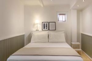 - une chambre avec un lit doté de draps blancs et une fenêtre dans l'établissement Keramidogatos Manos Guest House, Corfu Old Town, à Corfou