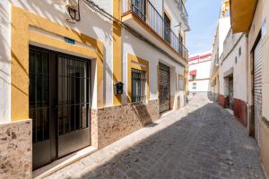 eine Gasse in einer Altstadt mit gelben und weißen Gebäuden in der Unterkunft Acogedor apto junto a la Alameda in Sevilla