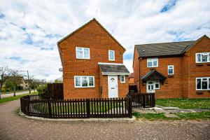 a brick house with a black fence in front of it at Milton Keynes for Families and Contractors with Private Parking in Shenley Brook End