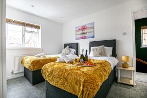 two beds in a room with champagne and fruit on a tray at Milton Keynes for Families and Contractors with Private Parking in Shenley Brook End