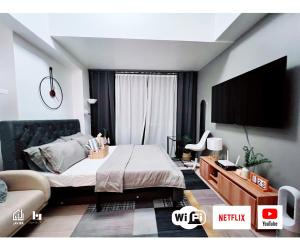 a bedroom with a bed and a flat screen tv at Casa de Lorille Eastwood Cozy Studio with Amazing view Free WiFi & Netflix Access in Manila