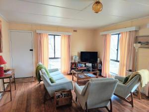 uma sala de estar com cadeiras, um sofá e uma televisão em Gidget's Place em Surf Beach