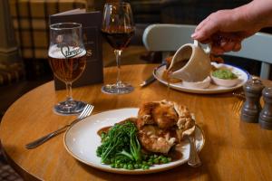 a table with two plates of food and a glass of wine at The Kingslodge Inn - The Inn Collection Group in Durham