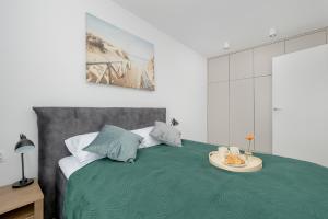 a bedroom with a green bed with a plate of food on it at Modern Apartment with Balcony and Parking by Noclegi Renters in Mielno