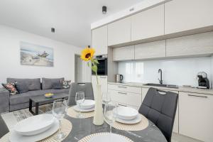 a kitchen and living room with a table and chairs at Modern Apartment with Balcony and Parking by Noclegi Renters in Mielno