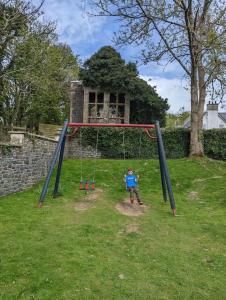 a boy on a swing set in a yard at Hill View in Ballantrae