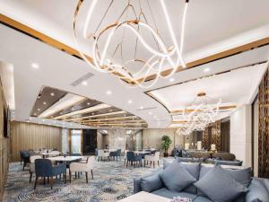 a hotel lobby with tables and chairs and a chandelier at Swissôtel Shenyang in Shenyang