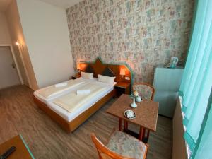 Rathaushotel في آيبنشتوك: غرفة نوم بسرير وطاولة وكراسي