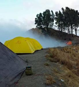 a group of tents on a hill with mist in the background at RINJANI EXPEDITION BASECAMP in Masbagik