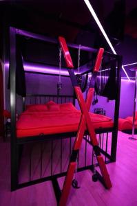 czerwone łóżko piętrowe w pokoju z fioletowymi lampkami w obiekcie BDSM apartmán v Bratislave -ADULTS ONLY w Bratysławie