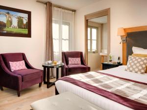 a hotel room with a bed and two chairs at Hotel Castel Maintenon in Maintenon