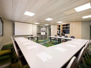 una sala conferenze con tavoli, sedie e lavagna bianca di ibis Styles Bordeaux Begles a Bègles