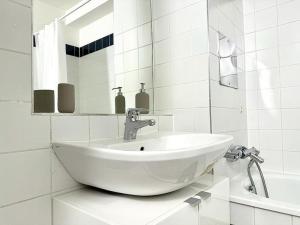 ein weißes Badezimmer mit einem Waschbecken und einem Spiegel in der Unterkunft Chic Apartment - Quiet Area - Next to Hospital in Wien
