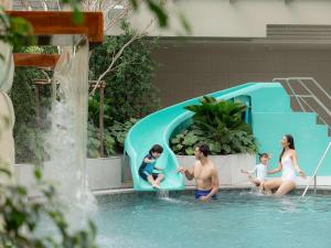 a family playing in the water in a swimming pool at Novotel Living Bangkok Sukhumvit Legacy in Bangkok