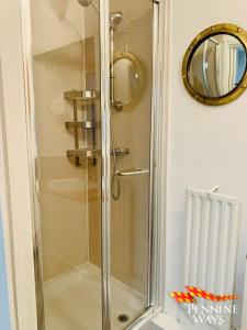 a shower with a glass door in a bathroom at The Nookery - Cosy Cottage in the Heart of Town in Alston