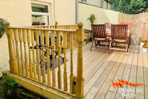 a wooden deck with two chairs and a table at The Nookery - Cosy Cottage in the Heart of Town in Alston