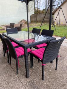 une table en verre avec des chaises matelassées roses et un parapluie dans l'établissement Le Refuge de l'Ours, à Baerenthal