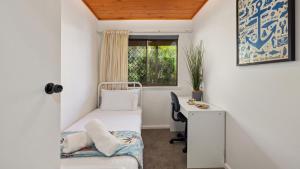 a bedroom with a bed and a desk and a window at Nelson on Nelson in Nelson Bay