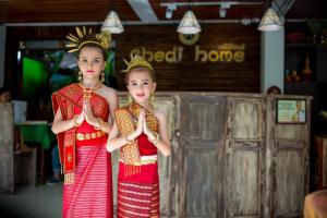 dos chicas vestidas de rojo y oro sosteniendo sus manos arriba en Chedi Home -SHA Extra Plus, en Chiang Mai