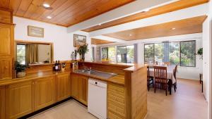 a kitchen with wooden cabinets and a dining room at Nelson on Nelson in Nelson Bay