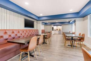 a waiting room with tables and chairs and a couch at Super 8 by Wyndham Orlando Near Florida Mall in Orlando