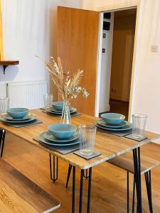 a wooden table with blue bowls and plates on it at Summer Vibes 1 Bedroom MCR city. in Manchester