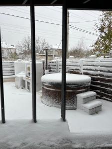 eine schneebedeckte Terrasse mit einem Tisch und einer Treppe in der Unterkunft Vilgrand in Vatra