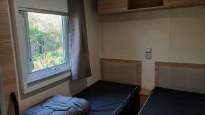 a small room with a bed and a window at Mobil-home -Clim, TV, LV- Camping LE LAC DES RÊVES 4 étoiles - MH-A009 in Lattes +4 photos