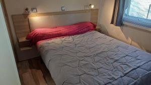 a bedroom with a bed with a red blanket on it at Mobil-home (Clim, Tv, Lv)- Camping Lac des Rêves 4* - 009 in Lattes