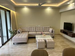 uma sala de estar com um sofá e uma televisão em The Pearl Club Resort em Santiniketan